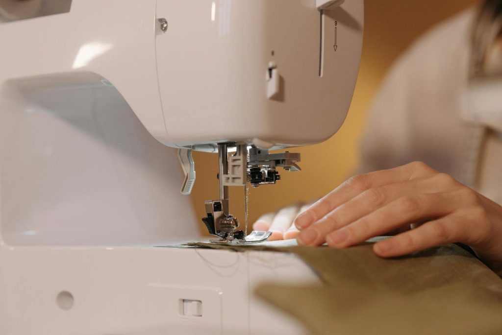 A detailed view of hands sewing fabric on a sewing machine, showcasing craftsmanship.